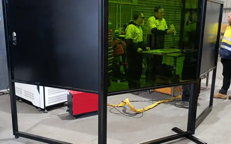 Enclosed laser welding cell with an interlocked safety door that stops the laser when opened